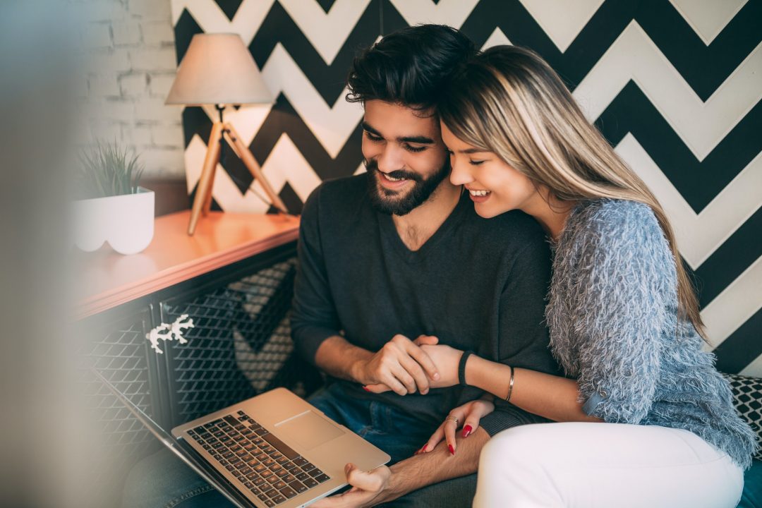 Casal assistindo a um filme no notebook, conectado na fibra da LLRD