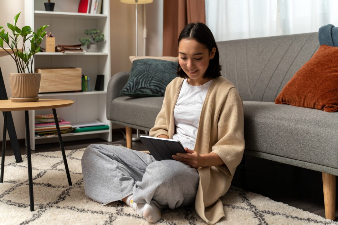 Mulher usando tablet sentada na sala de casa